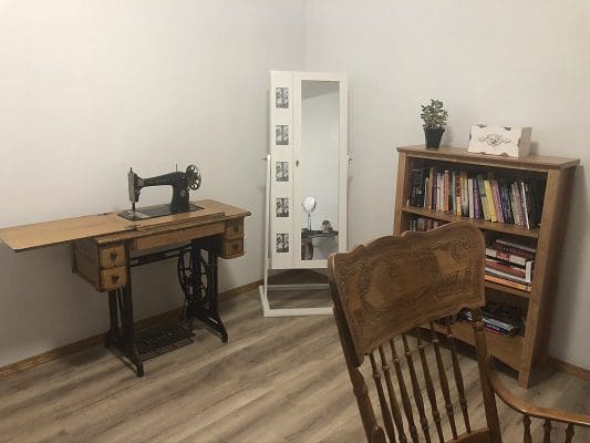 A sewing room with a sewing machine and bookshelf.