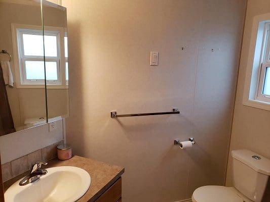 A bathroom with a toilet, sink and window.