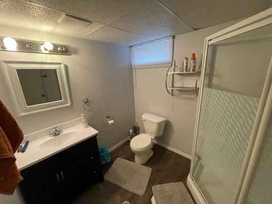 A bathroom with a toilet, sink and shower.