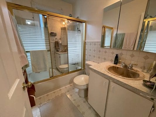 A bathroom with a toilet, sink and shower.