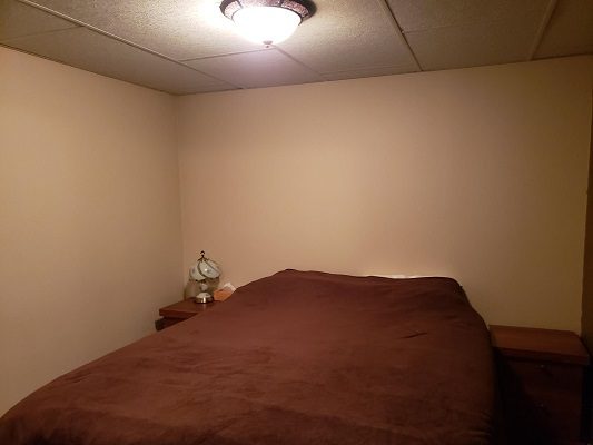 A small bedroom with a bed and a lamp.