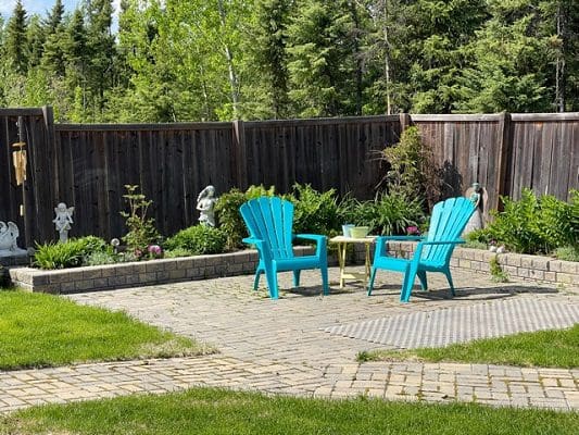 A backyard with blue chairs and a wooden fence.