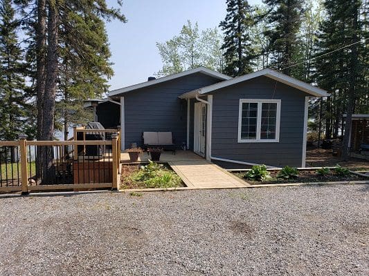 A cabin in a wooded area with a deck.