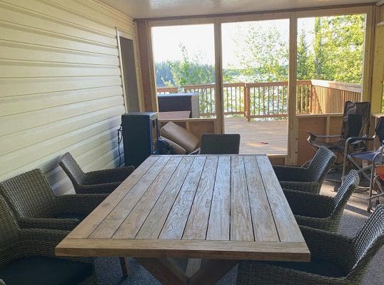 A screened in porch with a table and chairs.