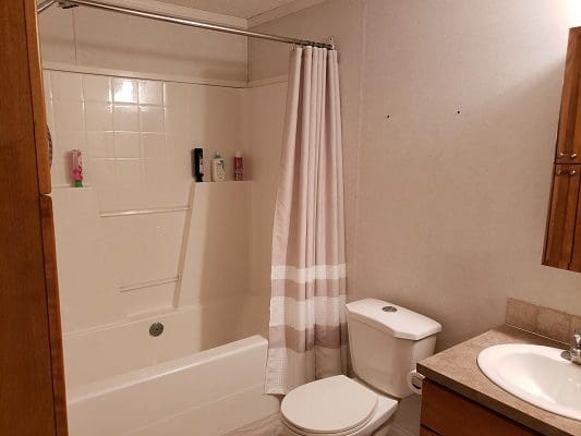 A bathroom with a toilet, sink and shower.