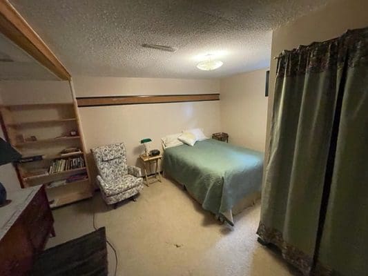 A small bedroom with a bed and a chair.