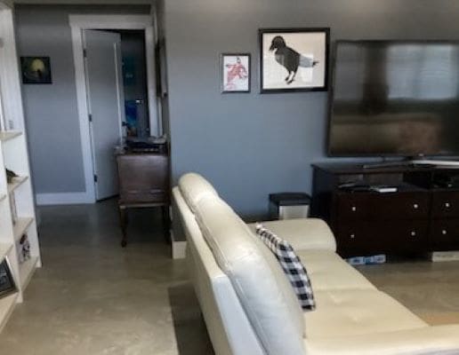 A living room with a white couch and a tv.