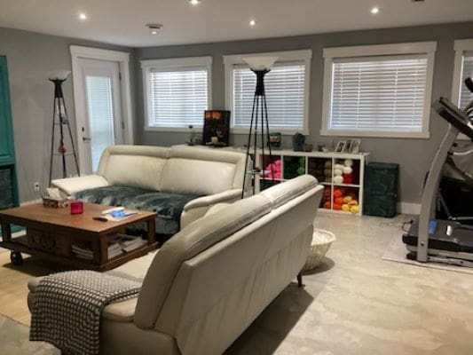 A living room with white furniture and a treadmill.