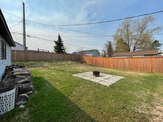 A backyard with a wooden fence and a fire pit.