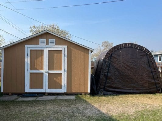 A tan shed with a tarp on top.