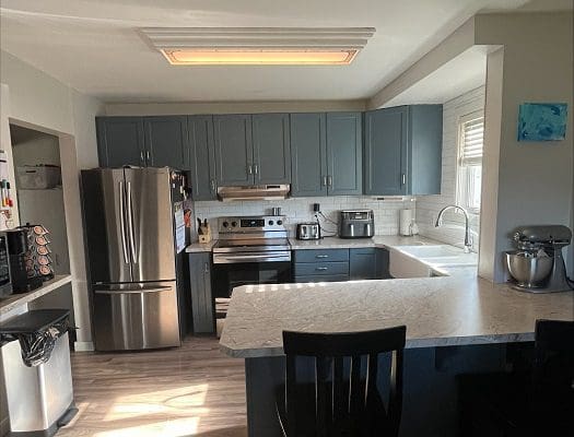 A kitchen with blue cabinets and stainless steel appliances.