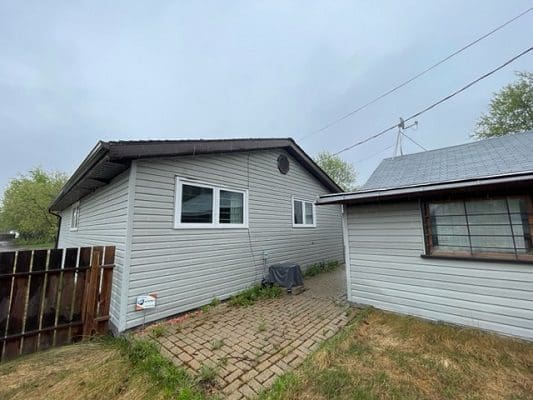 A house in a backyard with a fence and a garage.