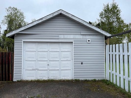 A white garage with a white picket fence.