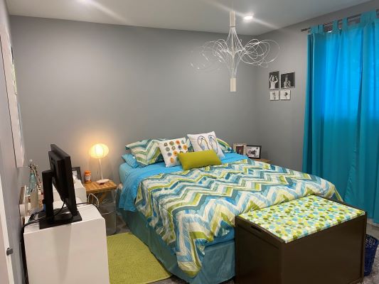 A blue and green bedroom with a bed and a desk.