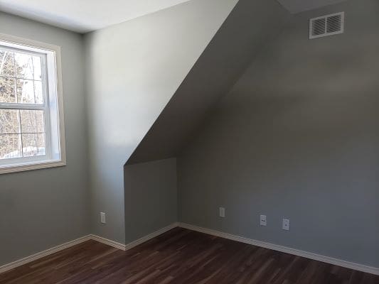 An empty room with hardwood floors and a window.