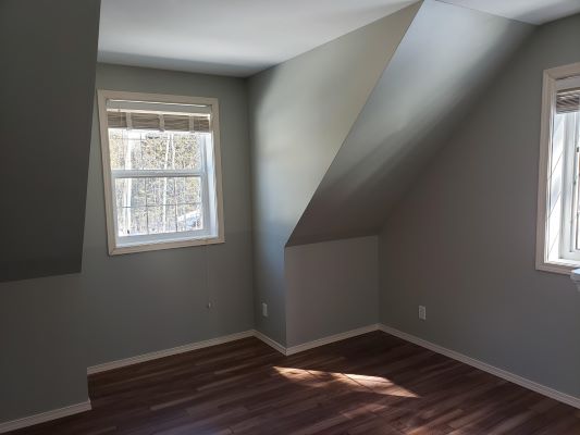 A room with two windows and hardwood floors.