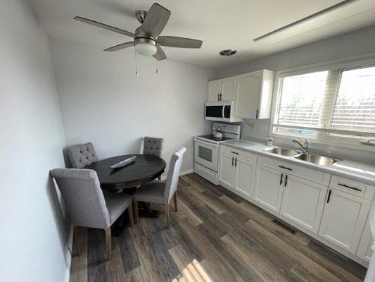 A kitchen with wood floors and a ceiling fan.