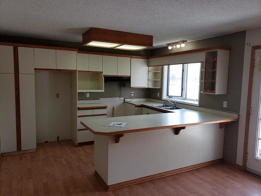 A kitchen with white cabinets and hardwood floors.