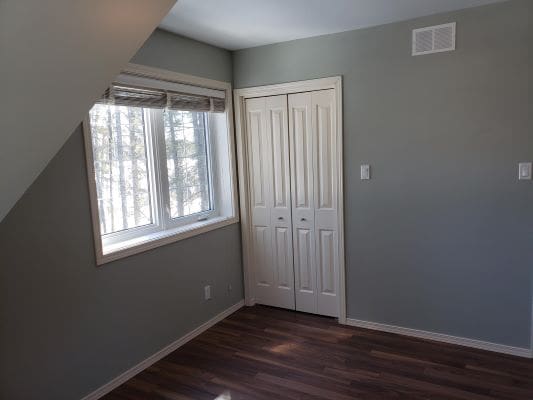 An empty room with wood floors and a window.