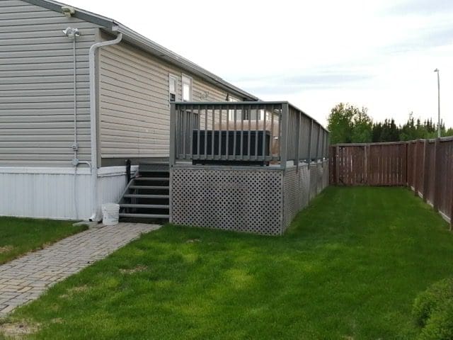 A house with a deck and stairs leading to a yard.