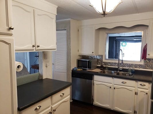 A kitchen with white cabinets and black counter tops.