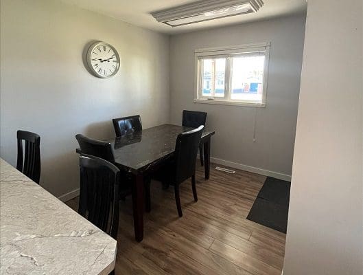 A kitchen with a table and chairs and a clock.