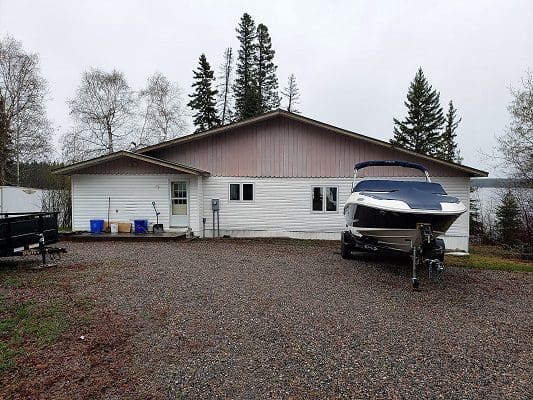 A house with a boat parked in front of it.