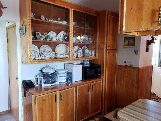 A kitchen with wooden cabinets and dishes on the counter.