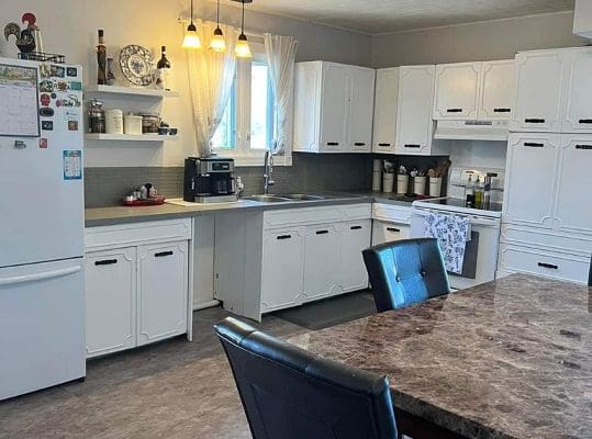 A kitchen with white cabinets and granite counter tops.