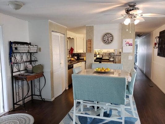 A kitchen with a dining table and chairs and a ceiling fan.