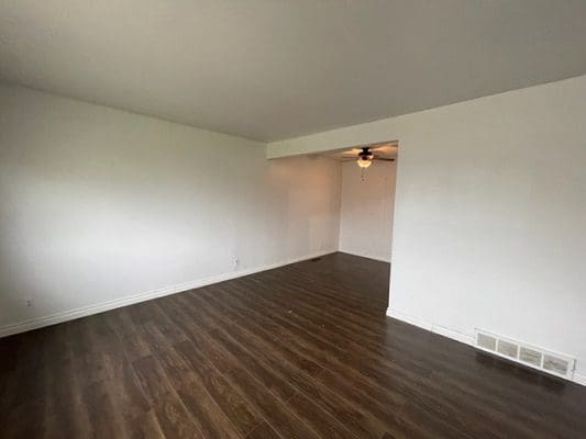 An empty room with white walls and hardwood floors.
