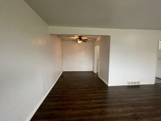 An empty living room with white walls and hardwood floors.