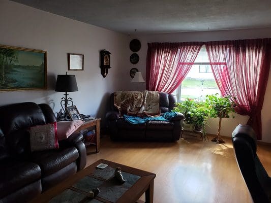 A living room with brown leather furniture and red curtains.
