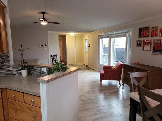 A kitchen and dining room with hardwood floors and a ceiling fan.
