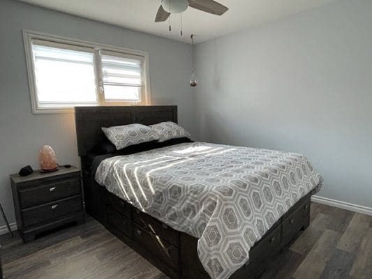 A bedroom with hardwood floors and a ceiling fan.