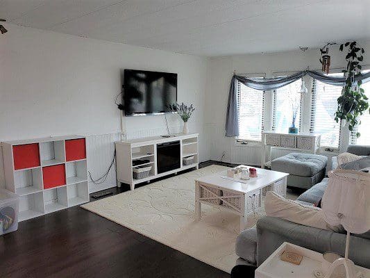 A living room with white furniture and a tv.