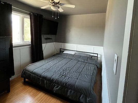 A bedroom with a bed and a fan in it.