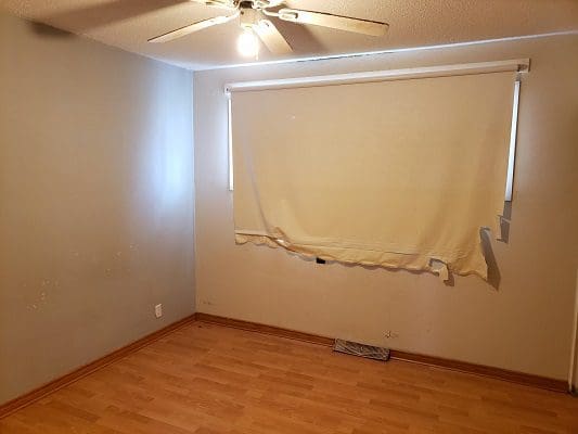 An empty room with hardwood floors and a ceiling fan.