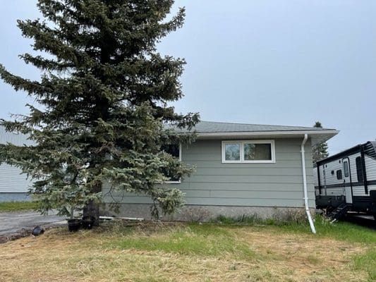 A house with a trailer parked in front of it.