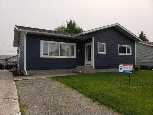 A blue house with a sign in front of it.