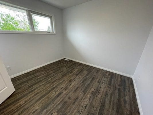 An empty room with wood floors and a window.