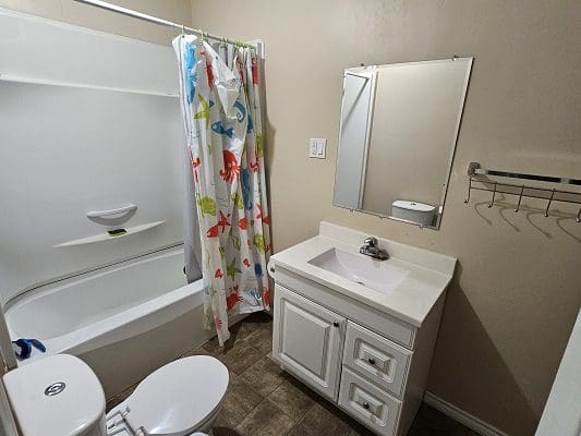 A bathroom with a toilet, shower, and sink.
