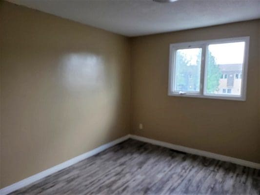 An empty room with wood floors and a window.