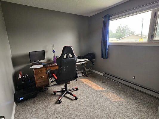 A room with a computer desk and a window.