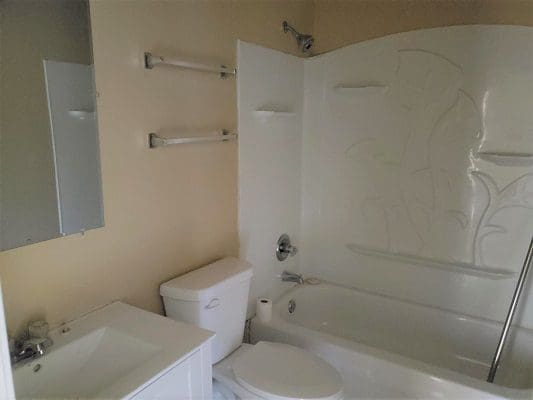A white bathroom with a toilet, sink and shower.