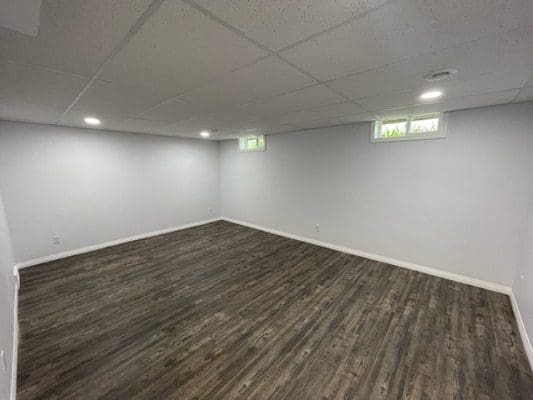 Empty basement with wood floors and white walls.