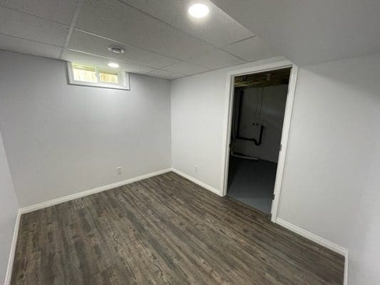 An empty room with wood floors and white walls.
