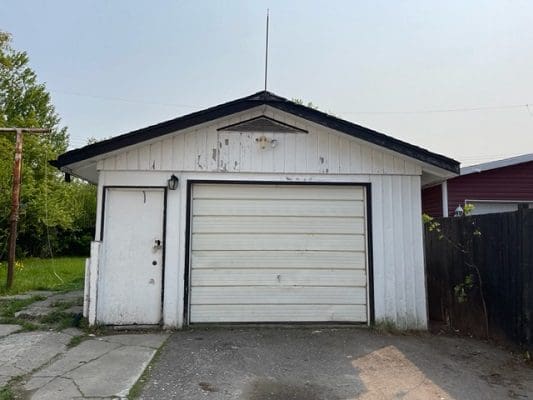 A white garage with a garage door in front of it.