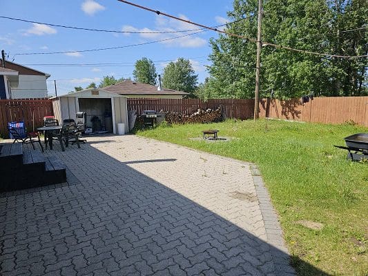 A backyard with a brick patio and a grill.