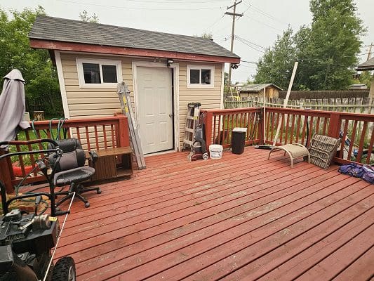 A backyard with a red deck and chairs.